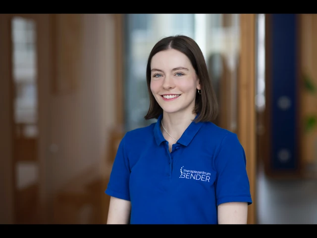 Junge Frau im blauen Polohemd vom Therapiezentrum Bender lächelt freundlich in Praxis.